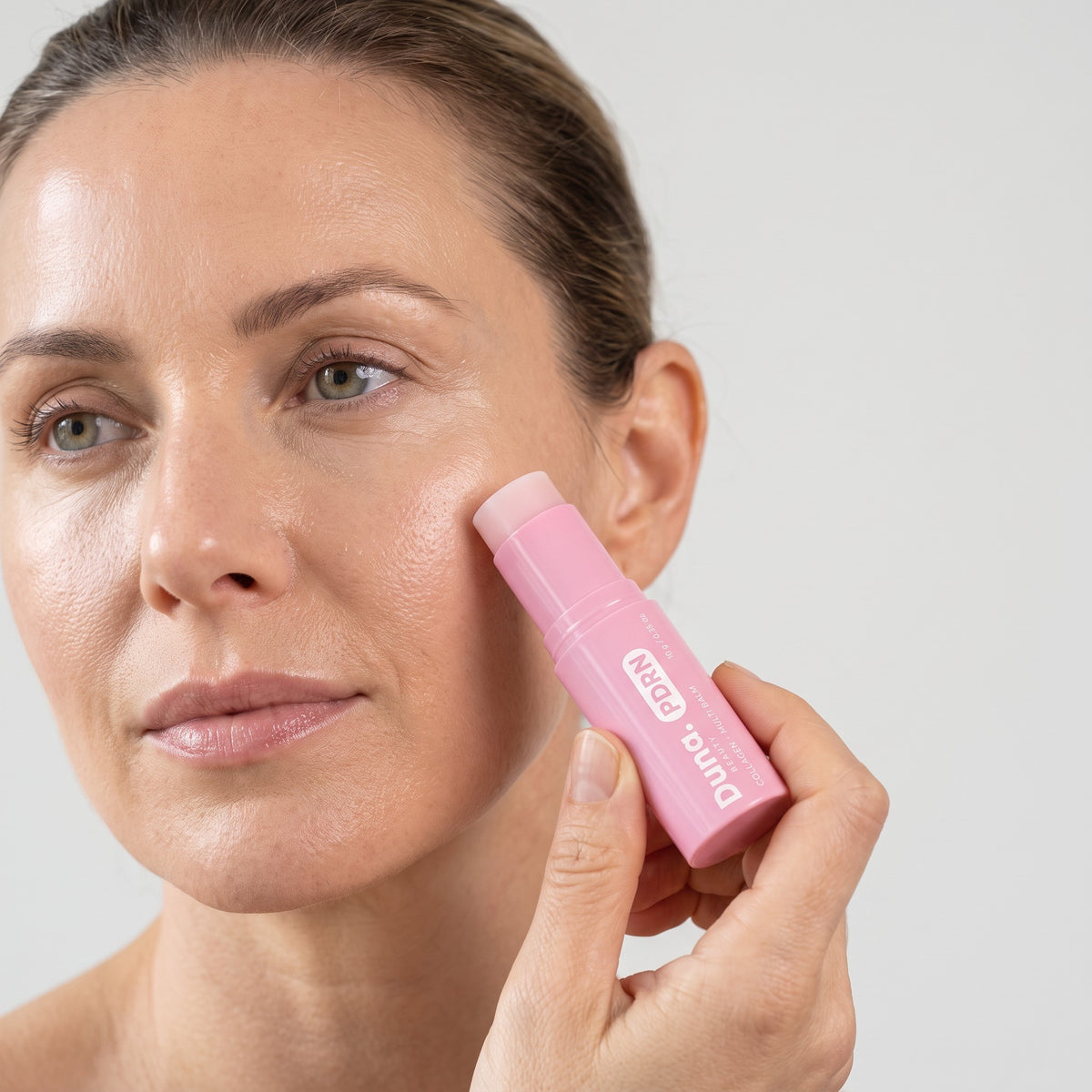 Woman swiping the Duna Beauty PDRN Collagen Multi Balm on her cheekbone